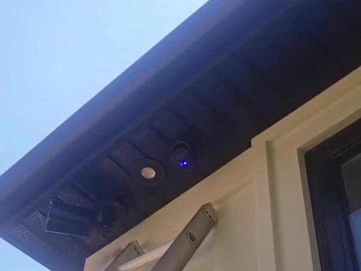 Technician on a ladder recovering security camera cables from a soffit