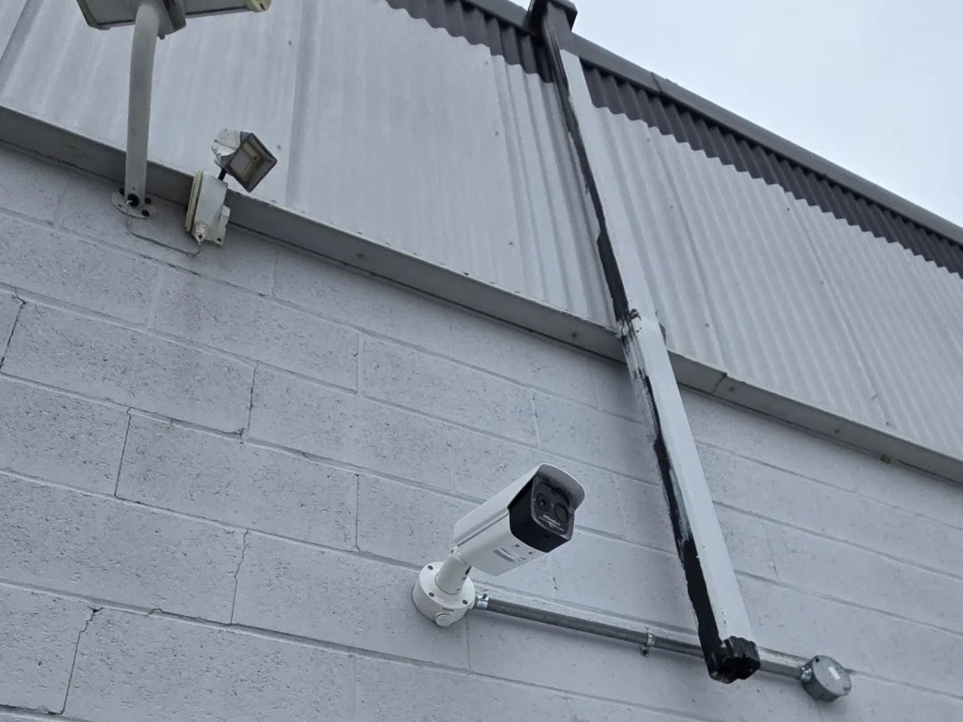Outdated security cameras on a warehouse wall before replacement