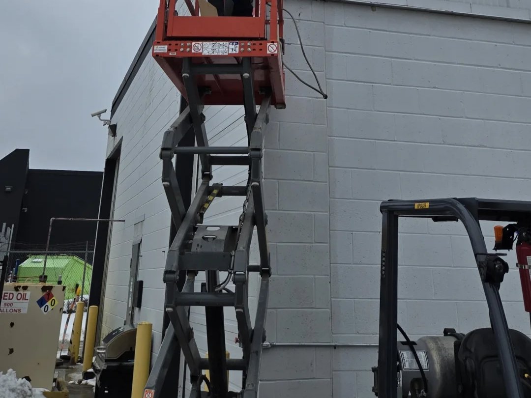 Installer on a scissor lift mounting a new camera on a warehouse